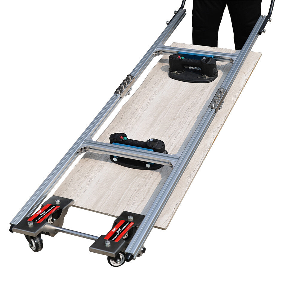 A large format tile installation dolly with grabo lifter, made of aluminum with swivel wheels and black and red components, being used to transport a tile.
